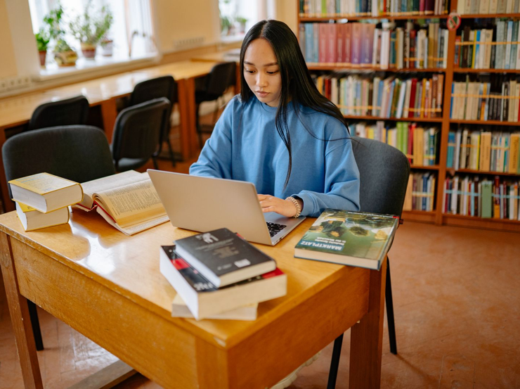 Student using a laptop at a library table.
