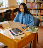 Student using a laptop at a library table.