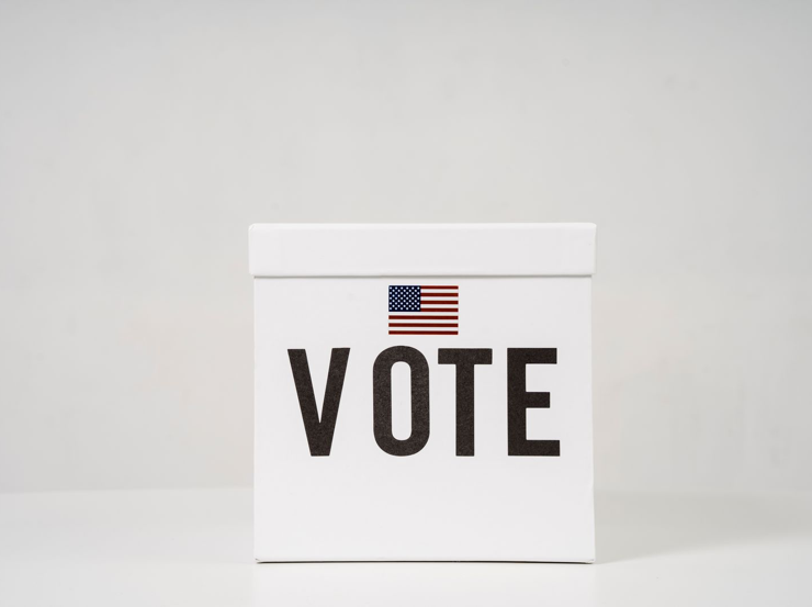 White ballot box displaying the word Vote and a US flag.